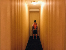 man with a backpack standing at the end of a hallway 