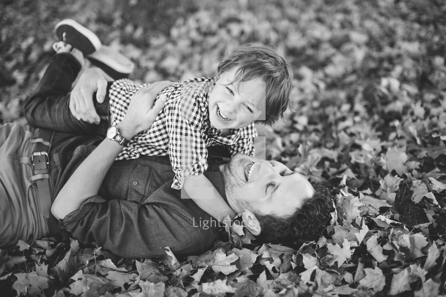 a father and son hugging in fall leaves 