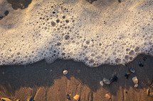 sea foam washing onto a beach 