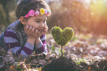 little girl planting a heart-shaped tree and dreaming of a beautiful future