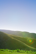 sun halo on green hills 