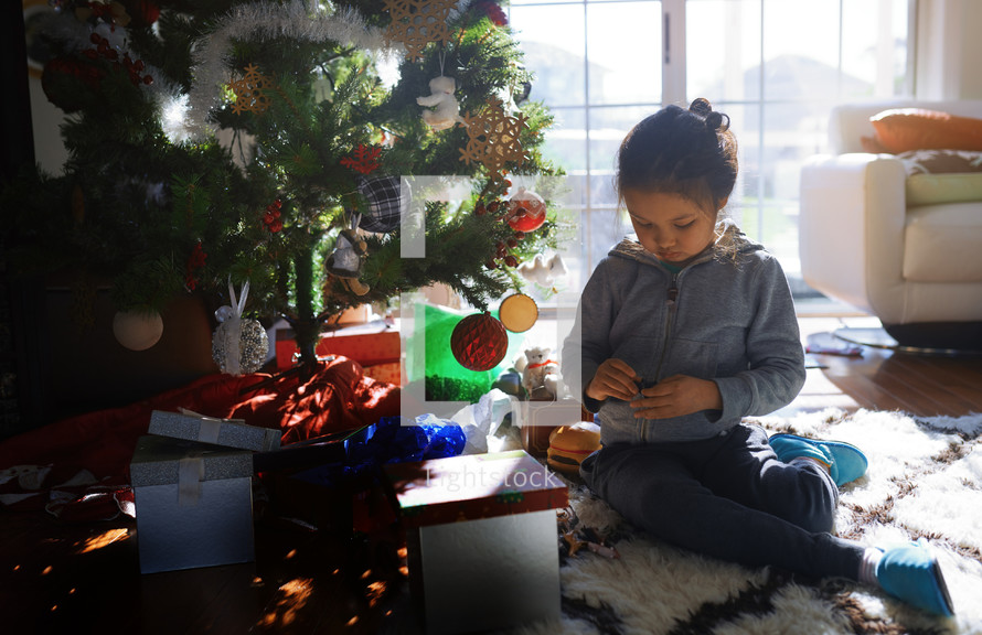 child playing with toys under a Christmas tree 