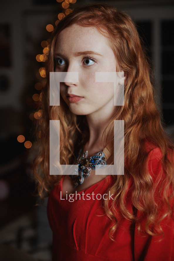 young woman standing in front of bokeh Christmas lights 