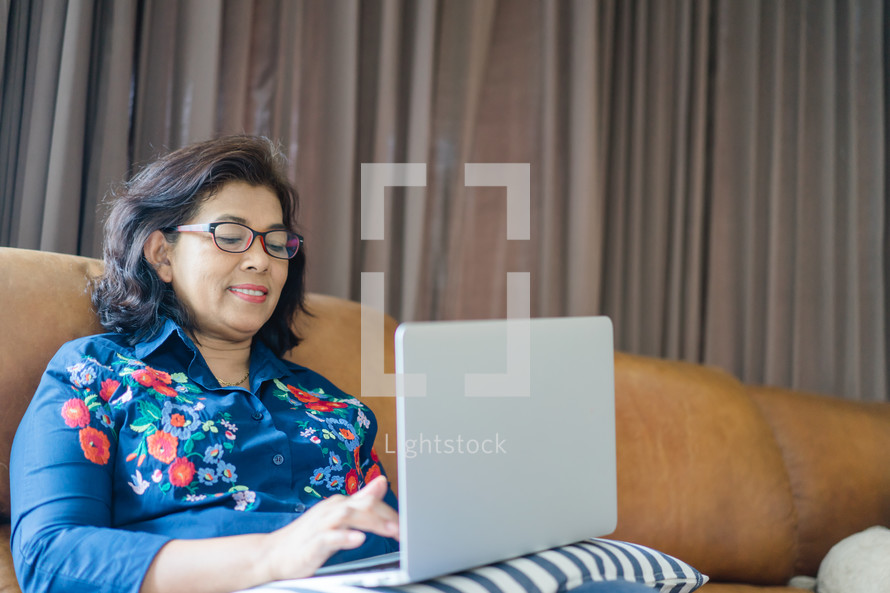 a woman sitting on a couch working on a laptop computer 