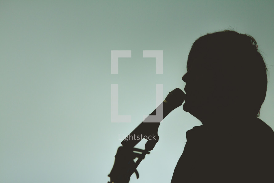 silhouette of a man singing into a microphone 