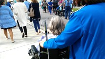 A hospital patient in a wheel chair with her Nurse care giver at a local Hospital with other patients going outside for fresh air and therapy. 