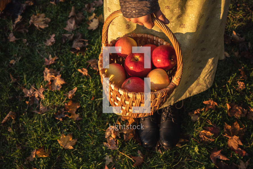 A woman carrying a basket of apples 