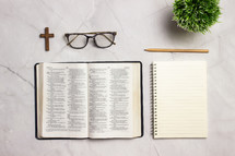 open Bible, notebook, and reading glasses on a desk 