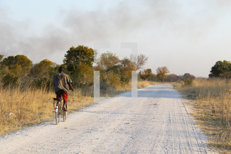 man riding a bike down a dirt road 
