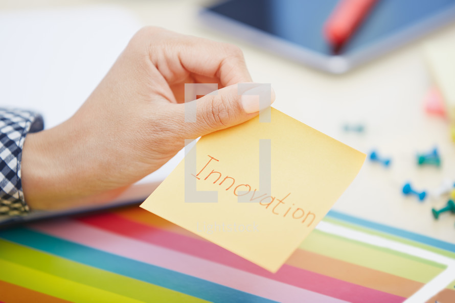 woman holding a sticky note with the word innovation 