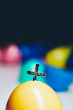 Cross emerging from a plastic Easter egg.