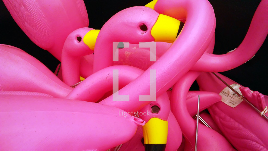 A group of Pink Flamingo plastic birds with metal stakes are gathered to put together 