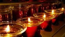 A row of red Christmas Candles lite for a Christmas Even Service or Prayer vigil candlelight service during church worship in an evening worship service at a local church during the holidays. 