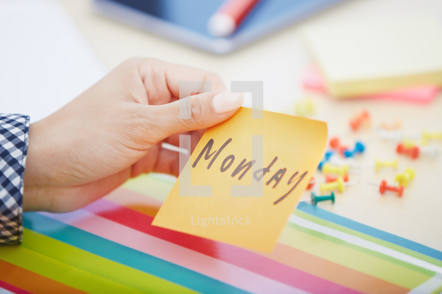 woman holding a sticky note with the word Monday 
