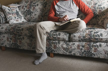 man sitting on a couch reading a Bible 