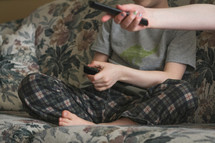 boy sitting on the couch holding a remote control 