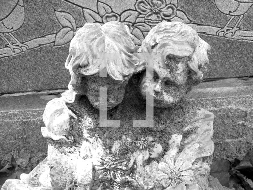 A Grave marker statue of two children, a boy and a girl, crying together at the grave of a dearly departed sibling or family member. Black and white photograph of this somber and tender image. 