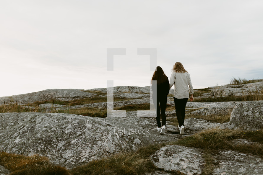 a couple walking on a rocky mountaintop 