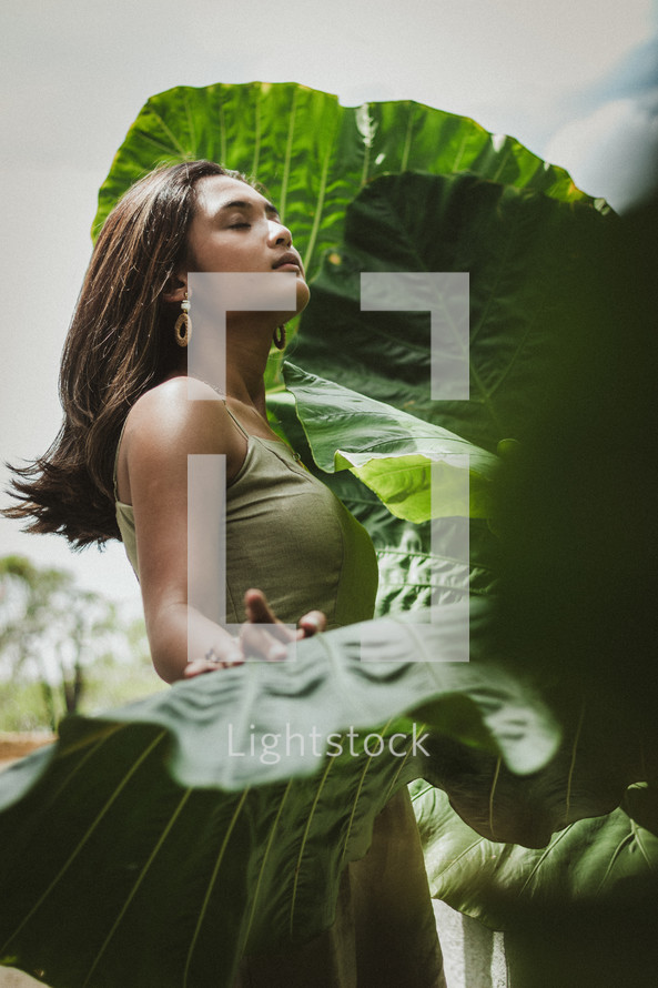 young woman standing between tropical foliage 