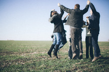 a group holding hands in a circle and jumping in the air in celebration