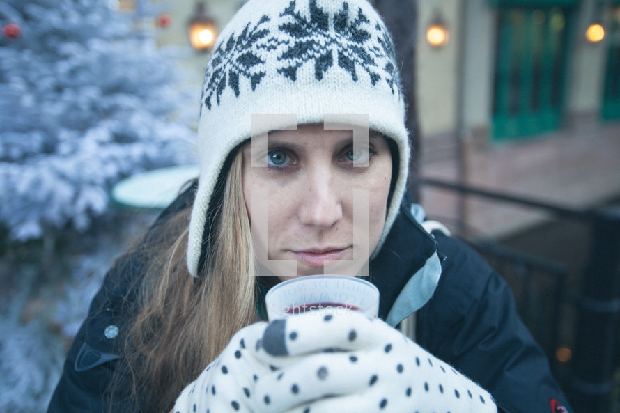 woman in gloves and winter hat holding a cup 