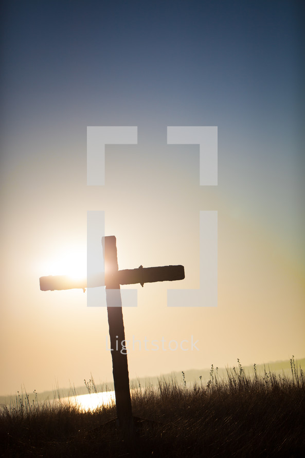 cross in a field at sunrise