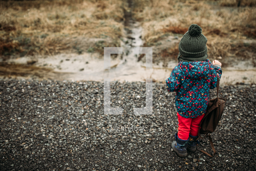toddler standing on a gravel road 