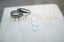 Two wedding rings set on top of a white bible.