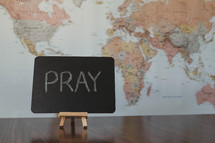 world map and word pray on a sign 