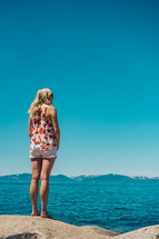 a woman standing on a rock looking out at Lake Tahoe 