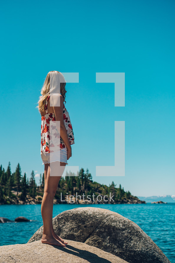 a woman standing on a rock looking out at Lake Tahoe 