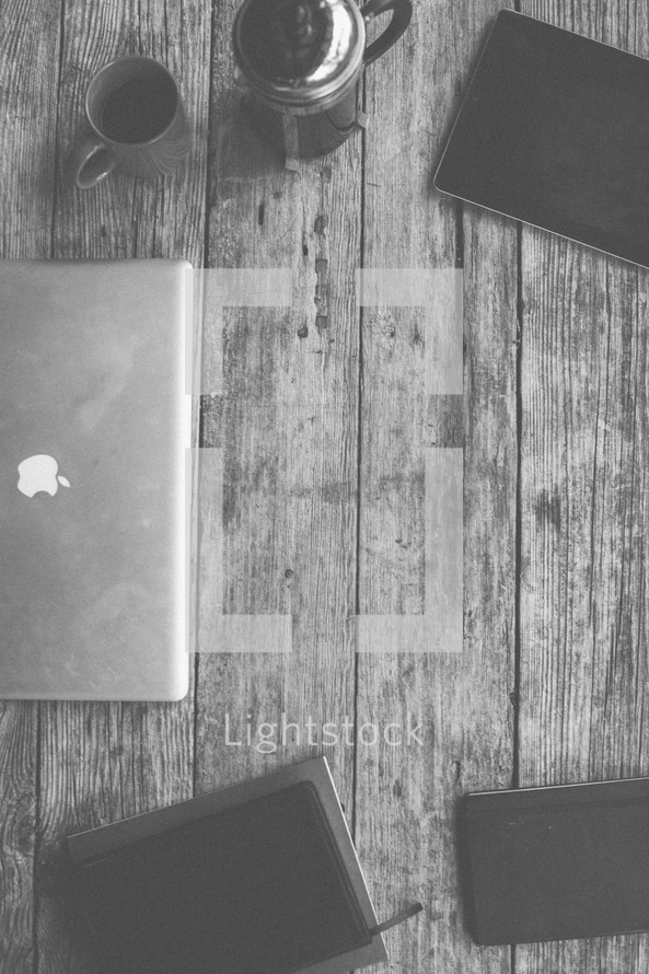 A laptop, bible, notebooks, iPad and coffee on a table