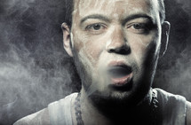 Man smudged by the dust smoking on a black background