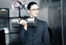 Serious businesswoman with heavy barbell
