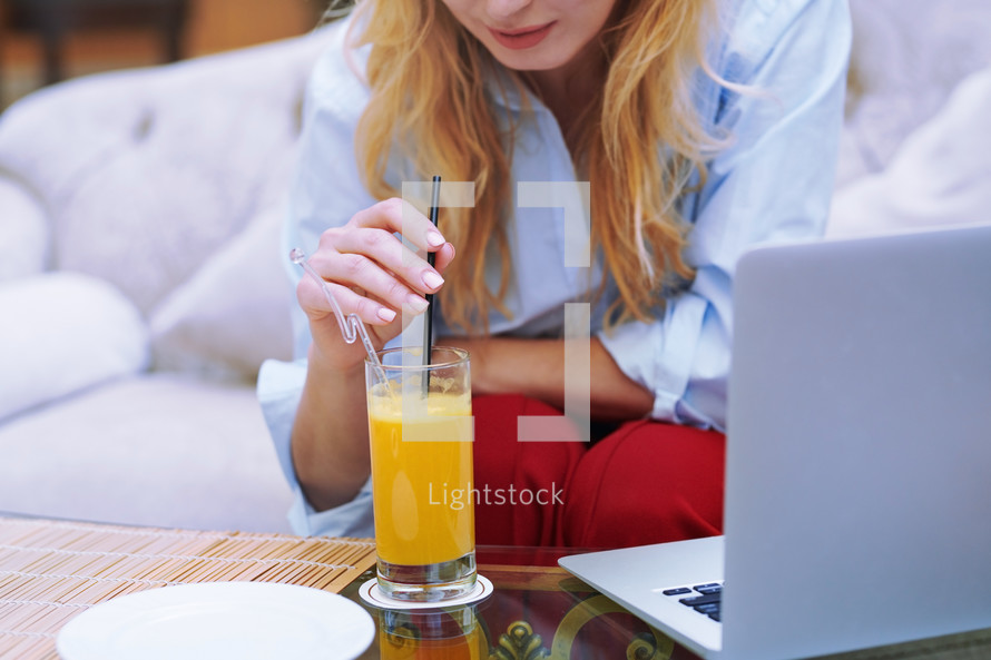 woman drinking orange juice in a lobby 