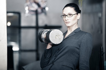 Serious businesswoman with heavy barbell