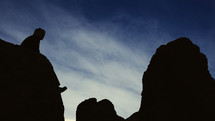 Silhouette of a man sitting on a rock formation. 