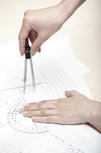 woman using a compass on blue prints 