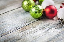 green, red, and white Christmas ball ornaments on a wood background 