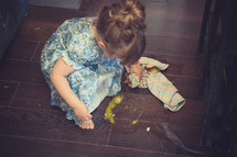 toddler girl cleaning up a mess on the kitchen floor