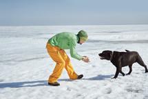 man and his dog playing in snow 