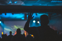 silhouettes of people with hands raised during a worship service 