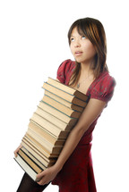 Young schoolgirl carrying numerous heavy books
