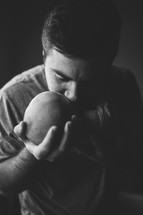 father kissing and holding a swaddled newborn 