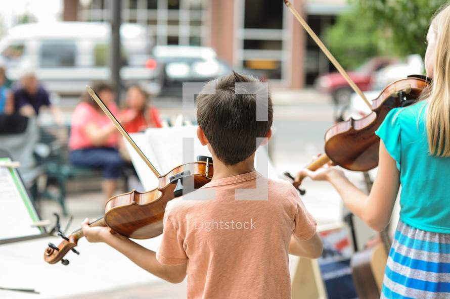 children playing violins outdoors 