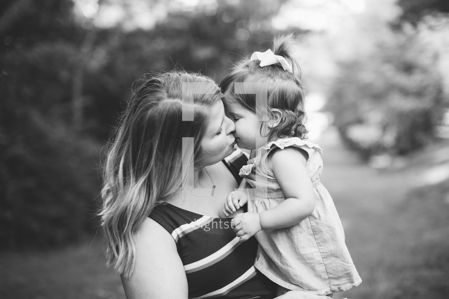 a mother kissing her toddler daughter in black and white 