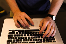 hands of a man typing on a laptop computer 