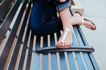 a woman's feet in flip flops on a bench