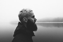 man with a thick beard in front of a lake 