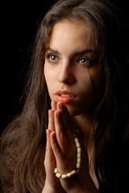 Praying hands of repentant woman with religious string of beads